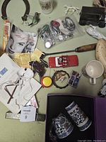 Top down view of various collectibles and items on a table, showing toy fire truck, assorted pins, ceramic mugs, horse figurine, wooden shoe, documents, and tools