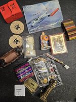 Clear view of assorted souvenirs and collectibles including carved items, playing cards, fabric pouch, and keychains laid out on a black textured surface.
