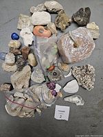 Overview photo showing the lot of assorted rocks, stones, shells, some wrapped in plastic bags, variety of textures and colors.