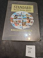 Cover of the Standard World Stamp Album showing title and globe composed of stamp images.