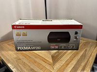 Photo of the front and sides of the Canon PIXMA MP280 printer box showing branding, model number, and product features.