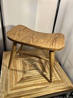 Wooden stool angled view showing curved seat and leg design