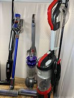Three vacuums side by side: generic black stick, Dyson Ball corded upright, Dirt Devil Razor+