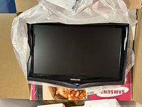 Samsung 22 inch LCD TV screen resting on packaging materials, showing front view of TV with Samsung logo and black bezel.