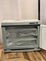 Side view of the UV towel warmer showing interior shelves wrapped with towels covered in bubble wrap.