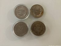 Four Canadian tokens shown from front with visible embossed details including salmon, bighorn sheep, and commemorative dates.