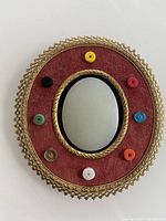 Close-up view of the oval central jade piece surrounded by 8 colored jade beads on a red fabric background within an ornate antique gold metal frame.