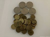 Overview of approximately 30 silver, brass, and bronze casino tokens of various sizes and designs.