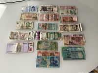 Collection of multiple banknotes spread out showing various sizes and colors with visible wear and folding.