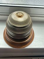 Side view of the music jewelry box showing the metal layered lid with central decorative accent on wooden base.