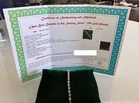 Certificate of authenticity and appraisal propped behind green velvet stand with bracelet draped.