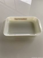 Rectangular white Pyrex baking dish with handles, showing the interior and some signs of use.