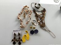 Overview of the vintage jewelry pieces on a white surface, showing necklaces, watches, earrings, and a ring.