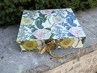 Floral keepsake box with ribbon tie on stone surface outdoors