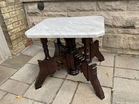 Front angle view of the marble top table showing the detailed turned wood legs and marble surface