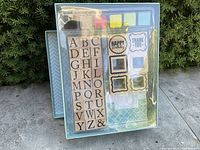 Full kit showing packaging with alphabet stamps on left, sentiment stamps on right, ink pads on top left, cards and envelopes background.