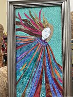 Full view of framed quilted angel art piece with intricate colorful fabric strips and painted angel face.