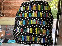 Full front view of the colorful square quilt with strip piecing and polka dot background, hanging outdoors.
