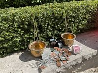 Wide view showing two brass hanging pots, wire rolls, plant signs, and decorative rosemary sign on stone ledge outdoors