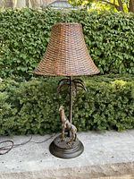 Full view of the lamp with rattan shade on outdoor surface, showing overall shape and color.