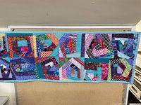 Full view of the quilt runner displaying the patchwork design and solid teal border.