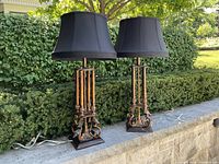 Photo showing pair of large decorative lamps with black fabric shades placed outdoors, highlighting overall appearance and size.