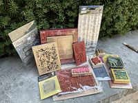 Photo of various wood-mounted rubber stamps and clear stamps outside box, showing designs of flowers, butterflies, and words like 'Happy Birthday'