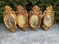 Front view of four oval papier mache frames with historical portraits and ornate gold designs