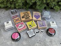 Overall view of wooden rubber stamps arranged with ink pads in various colors outside on concrete surface with greenery background.