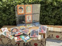 Binder pages with vintage baseball cards and loose cards in front of boxes