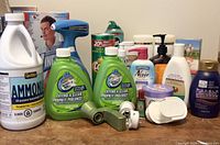 Front view of assorted cleaning and bathroom products including ammonia, Scrubbing Bubbles sprays, lotions, and soaps.