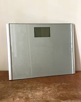 Front view of the large digital bathroom scale with a glass platform and a digital display screen near the top center.