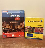 Front view of Berlitz Basic French boxed language course with photo of Arc de Triomphe at night, alongside yellow Rosetta Stone Totale French box.