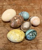 Photo showing all 7 marble eggs on wooden surface, displaying varied colors, sizes, and patterns