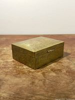 Closed vintage brass box with floral engraving on wood surface