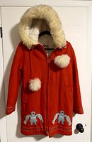 Front view of vintage red Gemini winter coat with hood featuring cream faux fur trim and pom-poms, zip front and embroidered birds at hem.