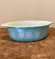 Side view showing blue exterior with white snowflake design and white rim of Pyrex dish