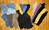 Overview of all clothing items laid flat showing various pants, dresses, tops, and jackets in different colors and fabrics