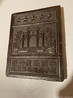 Front side of dark tea brick with embossed five stars, decorative arch, plants, and Chinese characters.