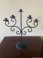 Front view of the black metal candelabra showing its five candle holders on curved arms with a twisted central stem.