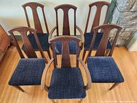 Front view of six chairs, four side chairs and two armchairs, showing blue fabric seats and wooden frames.