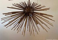View of bronze-toned metal Sputnik-style chandelier with multiple radiating rods and four integrated light sockets, hung from ceiling.