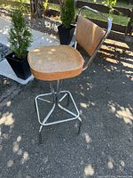 Side angle of vintage swivel stool showing padded seat and chrome tubular frame.