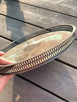 Side angle showing the pierced gallery edge and thin profile of the round silver tray.