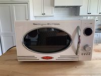 Front view of the microwave showing vintage design with oval window, chrome handle, and dial controls.