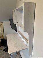 View of the desk with drop-down writing surface extended, showing the white wood grain finish and the flat surface with rounded edges.