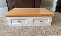 Front view of the wall mounted desk/end table showing two white drawers with metal handles and natural wood top.