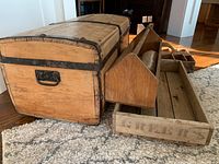 Photo of the wooden trunk showing front and side profile with metal bands and handle, along with the tool organizer and wooden pallet placed beside it.