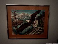 Full view of framed oil painting showing an American bald eagle flying near a nest with eaglets on a tree branch, set against a mountainous background.