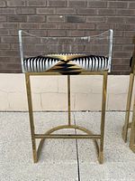 Front angle view of the lucite and brass bar stool highlighting the geometric patterned upholstered seat and lucite backrest.